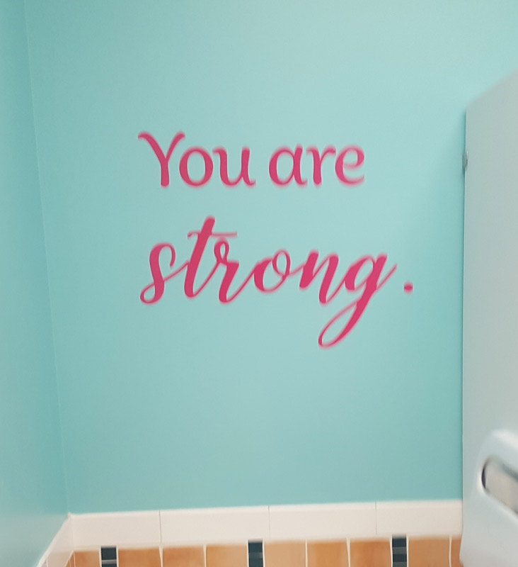 La calcomanía para pared en el Centro para niñas dice You are strong (Eres fuerte)