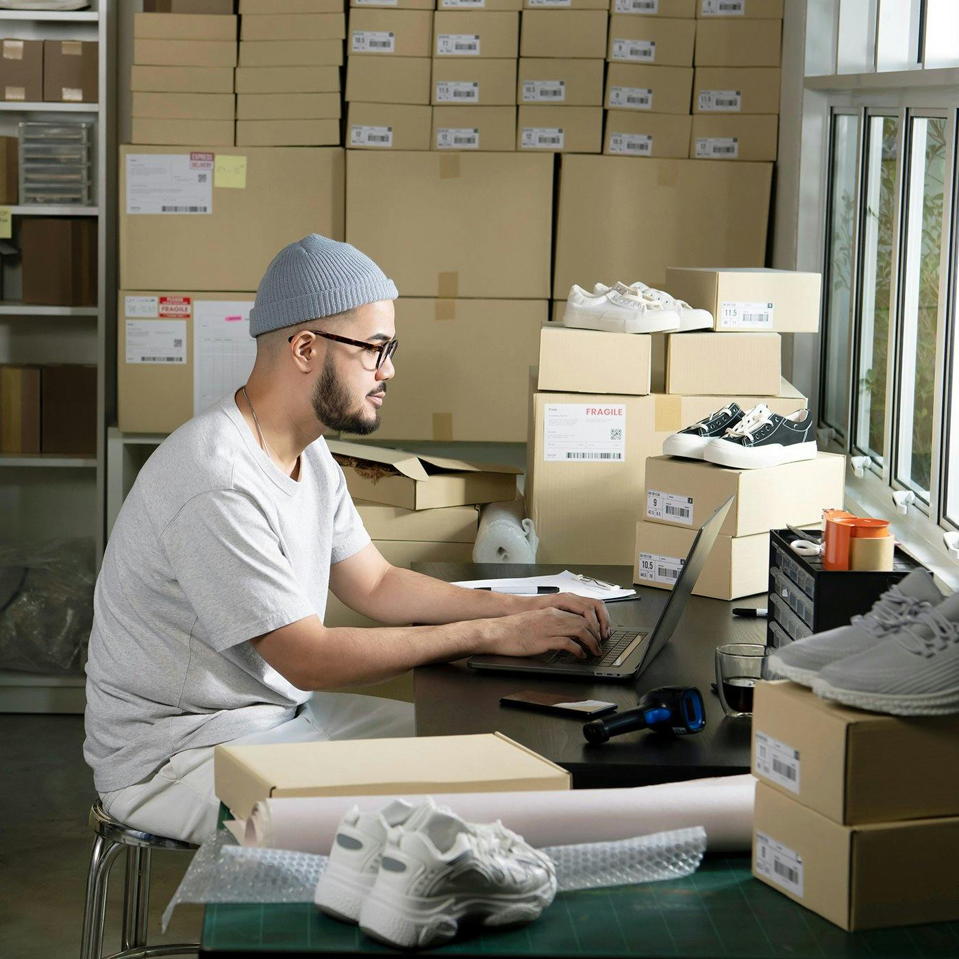 Un hombre trabaja en una laptop en una sala de envíos